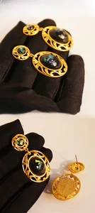 Detail of vintage gold hollow oval earrings with black gems and gold foil flakes