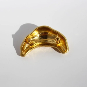 Golden croissant-shaped brooch in polished copper with textured finish and secure pin back