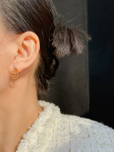 Close-up of double-layer gold teardrop earrings with zircon accents on ear