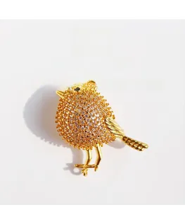 Macro detail of bird brooch showing gold-plated brass and pavé cubic zirconia setting