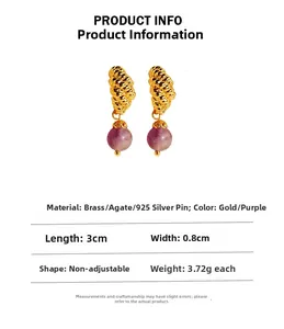 Detail of gold twist earrings with purple agate bead and 925 silver needle on white base