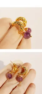 Detail view of gold spiral twist earrings featuring polished purple agate stone beads