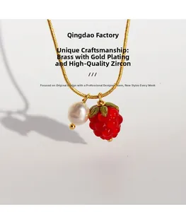 Close-up of gold-plated snake chain featuring a glass raspberry and pearl pendant