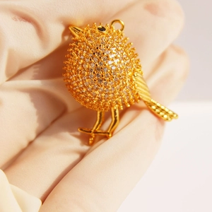 Sparkling gold bird brooch with full cubic zirconia stones and a black gem eye