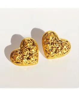 Dettaglio di orecchini vintage a cuore con motivi di rose a rilievo dorati