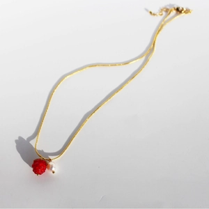 Gold snake chain necklace with red glass raspberry and white pearl pendants on white background