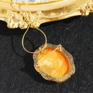 Vintage gold cameo brooch necklace with orange amber resin and intricate shell frame