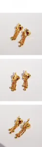 Macro detail of heart-shaped earring featuring red zircon center and gold tassel chains