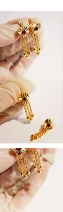 Detail showing heart-shaped gold earring with red zircon inlay and chain tassels