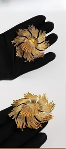 Macro detail of vintage gold-plated flower brooch showing intricate brushed metal texture