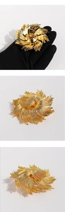 Macro detail of vintage gold floral brooch featuring multi-layered radiating petal structure