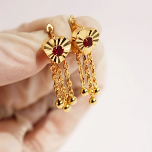 Golden heart drop earrings with red zircon and chain tassels on a white background