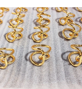 Close-up of gold adjustable knot rings with a polished mirror finish and irregular lines