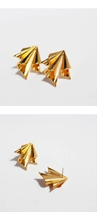 Macro view of gold irregular folded metal geometric stud earrings with brushed texture