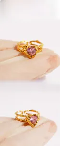 Macro view of textured golden ring with pink heart-shaped gemstone and lava design