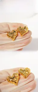 Detailed macro view of gold lava texture heart earrings with a central clear zircon inlay