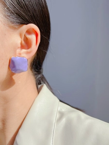 Detail of square purple enamel earrings with irregular texture and gold-edged finish