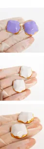 Detail presentation of geometric enamel earrings in lavender and creamy white colors