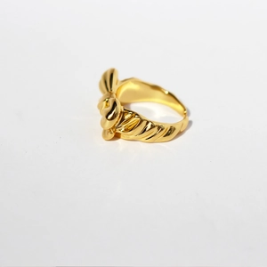 Bague dorée polie en forme de nœud, ajustable avec texture spirale sur fond blanc neutre