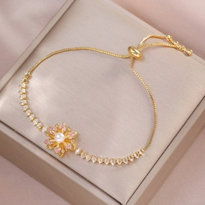 Elegant gold adjustable bracelet with flower charm featuring pink stones and pearl inlay