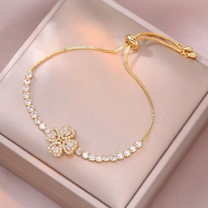 Macro detail of gold clover bracelet with sparkling white zircons on silk cushion