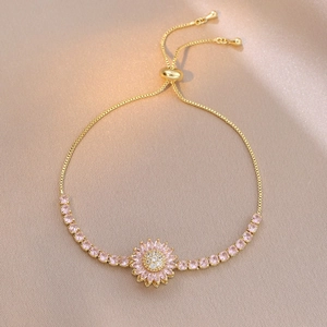 Detail of adjustable gold-tone bracelet with pink daisy charm and pink cubic zirconia
