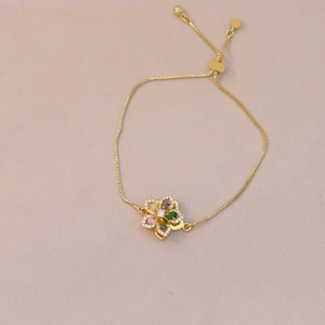 Detail view of gold box chain bracelet with colorful gemstone flower pendant and crystals