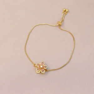 Close-up of adjustable gold flower bracelet with pink gemstone and micro-pave details