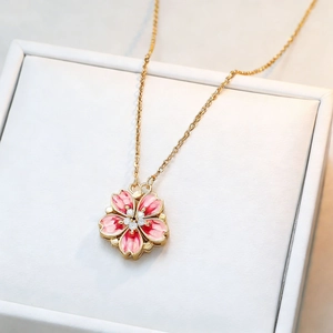 Pink enamel peach blossom pendant necklace with gold chain and crystals on a jewelry box