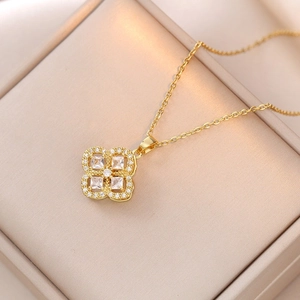 Close-up of golden necklace with spinning flower pendant and zircon clover design