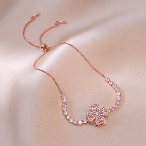 Dettaglio del bracciale a fiori in oro rosa con zirconi su seta color champagne