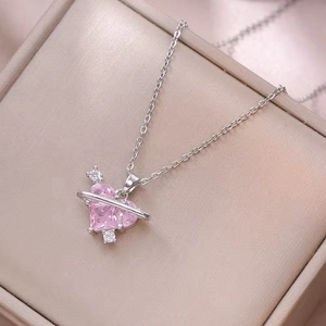 Macro shot of silver-tone Saturn necklace with pink heart crystal on velvet box