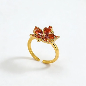 Golden maple leaf open ring featuring orange-red crystal stone inlay on a white background