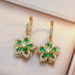 Détails de boucles d'oreilles fleuries dorées avec pierres vertes et cristaux pavés