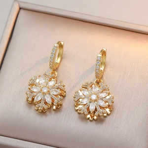 Détail macro de boucles d'oreilles flocon dorées avec cristaux dans une boîte à bijoux beige