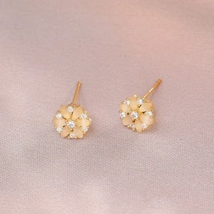 Dettaglio orecchini a fiore dorati con petali di opale giallo e strass su seta rosa