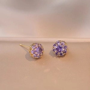 Détails macro de boucles d'oreilles fleurs dorées serties de cristaux de zircone violets