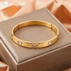 Detail of gold-plated stainless steel bangle with rhinestone and cross cut-out design