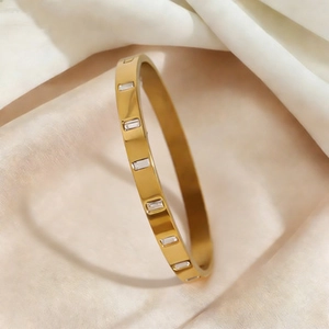 Détails d'un bracelet en acier doré avec des pierres en zircone cubique rectangulaires de taille baguette