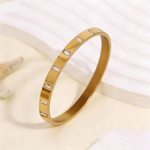 Vue détaillée du bracelet en titane plaqué or 18k avec zircons carrés sur texture blanche