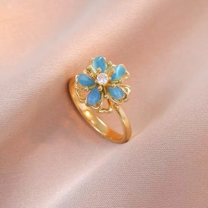 Macro shot of rotatable gold flower ring with blue cat eye petals and zircon center