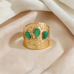 Gehämmerter Gold-Titanring mit grünen Wassertropfen-Malachitsteinen auf Satinhintergrund