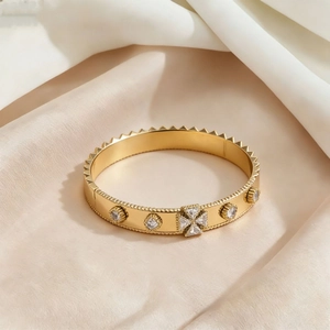 Gold titanium steel cuff bracelet with pyramid studs and quatrefoil clover inlay