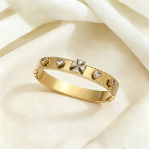 Gold plated titanium bangle with heart zircon stone and ribbed edges on silk background
