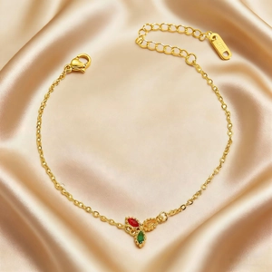 Detail of 18K gold chain bracelet with colorful drop-cut gems on satin fabric