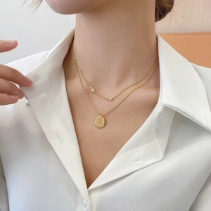 Double-layered gold titanium steel necklace featuring cross charm and round engraved tag