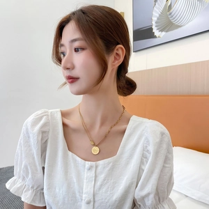Détail du collier double rang en titane doré avec pendentif pièce et fermoir à bascule