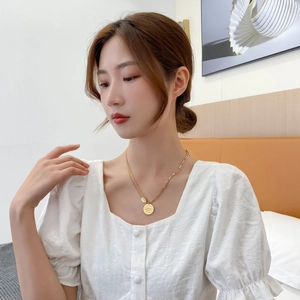 Gros plan du collier en titane doré avec pendentif circulaire gravé et fermoir OT