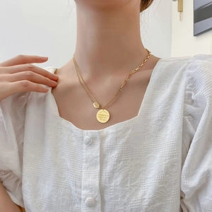 Gros plan détaillé du pendentif en pièce d'or à double couche et de la chaîne sur un mannequin