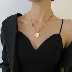 Détail du collier en acier titane doré avec pendentif rond gravé BELOVED et fermoir en T